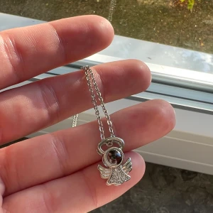 ”I love you” halsband - Gulligt halsband i fint skick som föreställer en ängel, inuti ängeln står det ”jag älskar dig” på alla språk.