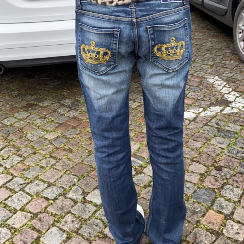 Blåa lågmidjade bootcut Victoria beckhamn jeans,med Guldiga kroner. Bra skick. Storlek 28, midje måtet är 74 cm och innerbenet är 80 cm. 🥰. Jeans & Byxor.