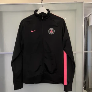 PSG Nike Zip-Tröja - Säljer nu en Svart-rosa PSG Zip-tröja från Nike som köptes för 1000kr för 2.5 år sedan på Zalando. Jättebra kvalite och bra skick. Bud mottages och för direktköp så går det för 799kr.