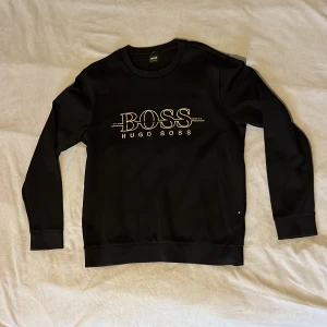 Hugo Boss Sweatshirt Black Gold - Skön Boss-tröja som är knappt använd. Säljer för jag köpte i storlek L men den krympt i min första tvättning. Den passar nu folk med storlek M.