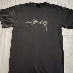 Loose fit T-shirt från Stüssy i en washed out grå/svart färg med vit distorted logo. Sparsamt använd. 