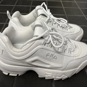 Fila Distruptor II Premium - Sparsamt använda Fila Disruptor II Premiums i triple white. Denna färg säljs ej längre och var exklusiv och limiterad. Superfint skick.