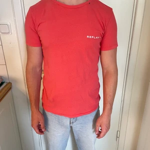 Röd/rosa t-shirt - Röd/rosa t-shirt med liten logga på bröstet samt stort tryck på ryggen. Väldigt skön och somrig. Ganska tight. Från replay.