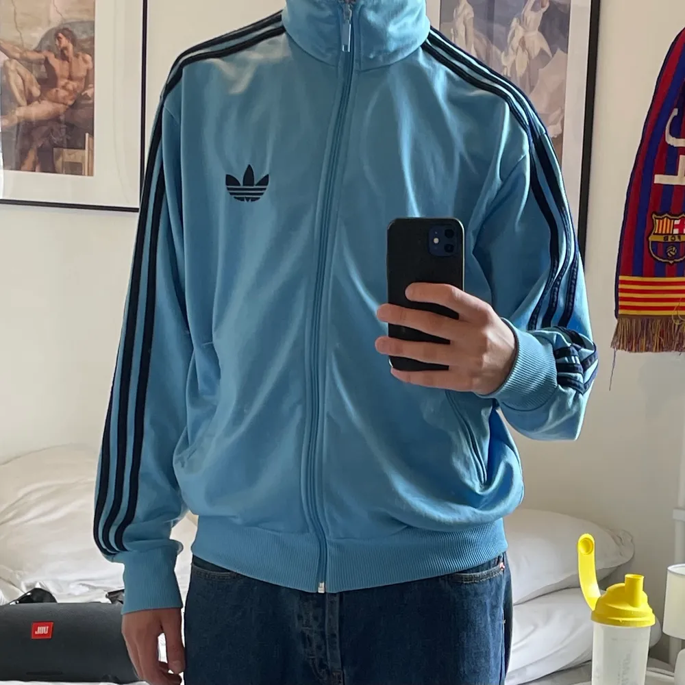 En tvärfet adidas kofta i storlek M. Koftan är ljusblå men byter toner av blå ganska mycket beroende på ljus och ibland glänser den också. Har tröttnat lite på den och försöker tömma min garderob så därför hamnar den här. . Tröjor & Koftor.