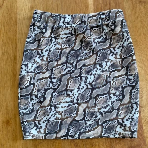 Ormmönstrad kjol - Kjol i ormmönster i brun, grön och vit. Storlek S men passar både xs och m då den är väldigt stretchig. Formar midjan och rumpan väldigt fint då den är formad efter kroppen. Bara att skriva om man har frågor ang. mått osv.