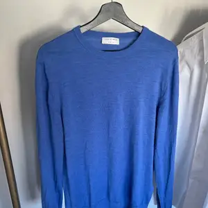 Stickad tröja från tiger of sweden i 100% merino ull. Färg: Elektrik blå. Passar herr M/L.