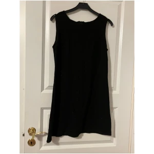 Kort svart klänning  - Kort svart klänning med skinande tråd i tyget.  från 90-talet. 