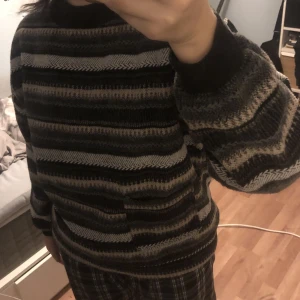 Randig stickad tjocktröja med ficka - Ett av mina plagg som verkligen tar emot att sälja! Superfin stickad tröja med ränder i neutrala/mörka färger. Den har en liten ficka och är ganska varm :))