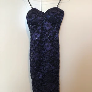 Snygg klänning - Snygg mörkblå klänning i svart spets med paljetter. Smal passform. Köpt på Nelly, använd fåtal gånger. Vaddar vid brösten.