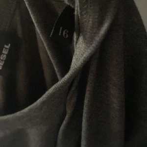 Diesel långärmad tröja, grå - Plagget har inga anmärkningar och är en barnmodell för ålder 16. Jag är nu 185 och 16 och plagget sitter lite fel i ärmarna så skulle kanske rekommendera 14 års-ålder