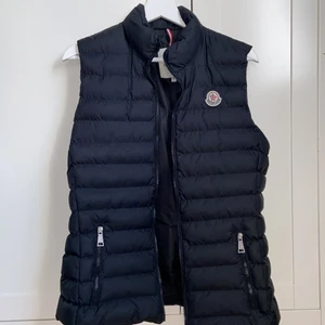 Moncler väst - En monclerväst som är svart och matt! Den är strl 2 vilket motsvarar M, men västen passar även som en S. Just nu har någon budat 2000kr