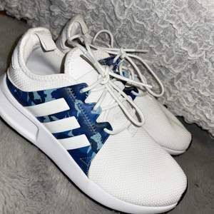 Helt oanvända vita adidas skor med kamouflage detaljer i blått.