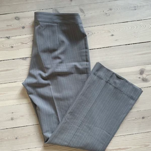 Pinstriped byxor  - Grå kristrecksrandiga byxor i jättefin modell, stl M. Inhandlade på Humana Second hand. Fint skick med undantag från dragkedjan som är lite trög att stänga. 