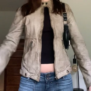Beige bikerjacka - 🖤 KLICKA INTE på köp nu, kontakta mig vid intresse! 🖤 Beige (med en grön ton) skinnjacka med snygga knappdetaljer, från märket Hollies! Perfekt till hösten/våren