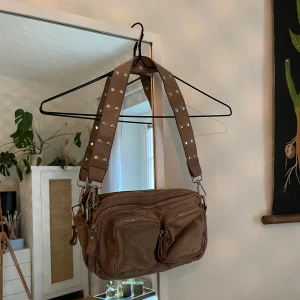 Väska i beige - Axelväska från Gina Tricot med ett kortare axelband och ett längre axelband. Ett stort fack och två mindre fack utanpå. Knappt använd, i gott skick. 