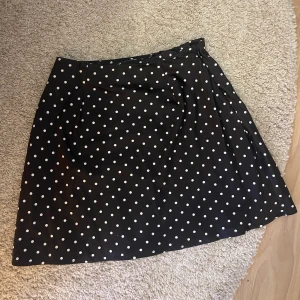 Svart kjol med vita prickar - Fin svart kjol med vita prickar. Finns små vita repor i kjolen, men syns bara om man kollar nära och noga. Säljer för 100 kr + frakt 29 kr. Använd ett antal gånger.