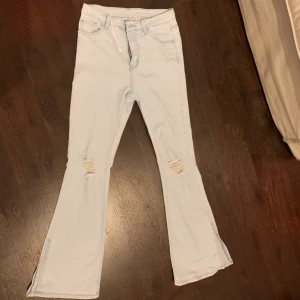 Blåa bootcut jeans med hål - Blåa tjata bootcut jeans med hål vid låren. Helt oanvända och de är lite öppna nere vid foten
