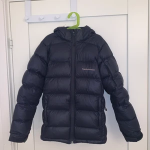 Peak Performance J Frost Down Jacket - Säljer nu min fina PeakPerformance dunjacka då den tyvärr har blivit för liten för mig som nu är en större S eller en M. Skulle säga att jackan är i nyskick då den inte har några defekter eller fläckar osv. Strl 160, sitter som en XS. 
