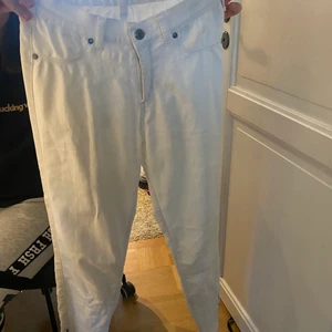 Vita jeans - Vita jeans jag aldrig använt. De är i fint skick. Längst ner på byxorna finns det en kedja som går att dra i (har man kedjan öppen så blir det lite som ett par bootcut jeans.