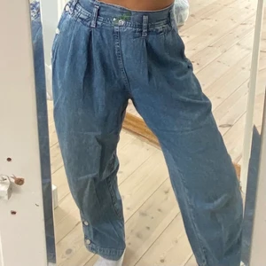 Jeans  - Jeans med knappar på sidorna av benen (obs själva benen går inte att knäppa upp). De knäpps i sidan och har en loose fit. Lite broderier på framsidan av midjan. Stl står M men uppskattar till S. Midjemått: ca 66 cm  Innerbenslängd: 67cm