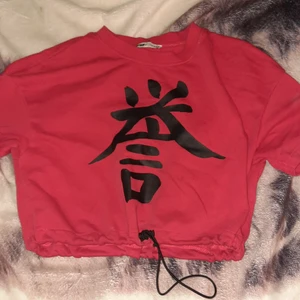 Magtröja - En röd magtröja med japanskt grafik på framsidan. Den har snören längst fram som man kan tajta och lossa tröjan på.Säljer för att jag inte vill ha den längre. Är i bra skick använd ett par gånger. 