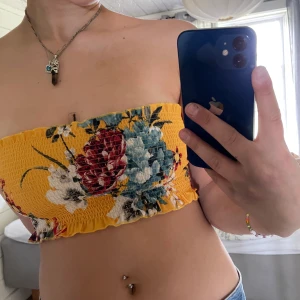 Blommig topp - Gul blommig topp utan axelband. Skulle rekommendera till folk med mindre bröst. Väldigt stretschig