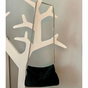 Handväska Mango - Svart handväska i Mocca med silvrig kedjerem. Köpt från Mango, inköpspris 399kr. Innerficka med dragkedja. Rymlig och fin väska som är varsamt använd.  Mått ca: L30cm, B 10cm, H 15cm  Material: 95% Bovine leather, 5% Polyuretan Innerfoder: 100% polyester