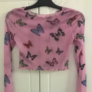 Oanvänd genomskinlig rosa topp med fjärilar, jättefin över ett linne. 