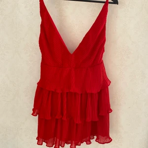 Röd klänning  - Röd klänning i plisserat tyg med volanger. Använd 1 gång. Bra kvalitet men har inte kommit till användning. ❤️
