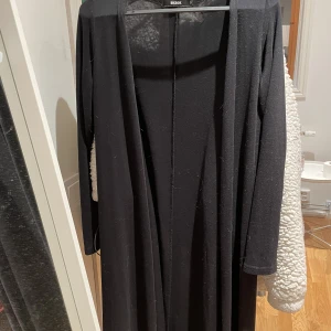 Lång svart kodta - Lång svart kofta från Bikbok. Storlek Small och inte använd på 1år