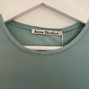 Otroligt fin, grönblå klänning från Acne Studios, stl S/36. Klänningen är i ett glansigt tyg och har ett jättefint fall. Aldrig använd. Helt ny med tagen kvar! Skicka PM för fler bilder :)  100% Viskos 