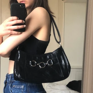 Supersnygg axelremsväska  - Svart axelremsväska i blankt lite läderliknande material. Detaljer i silver. Skriv för fler bilder! Köparen står för frakt. Kan mötas i Stockholm:) Buda! 