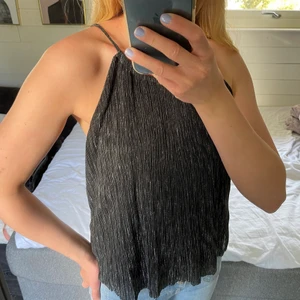 Glittrigt linne - Ett glittrigt linne som knyts i bak i storlek S. Jättebra skick!