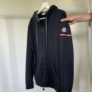 Moncler Hoodie - Hej! Säljer denna hoodie från Moncler. Den är i storlek XL men eftersom det är monclers storlekar är den i egentligen i M. Den är i fint skick, inga större skador. Hör av dig vid intresse eller fler bilder!🤗