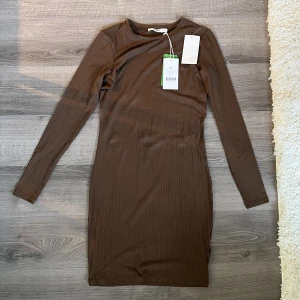 Brun kläning  - Säljer denna bruna klänningen från NAKD, oanvänd med tagg kvar. Storlek XS - stretchig. 