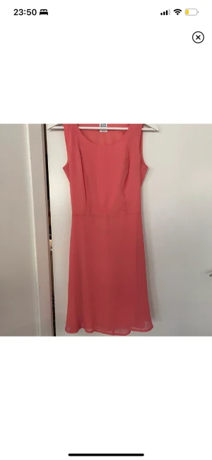 Klänning 34 - Underbar korallfärgad klänning ifrån Vero Moda. Storlek 34. Öppen i ryggen. Använd en gång på bröllop. Fint skick!