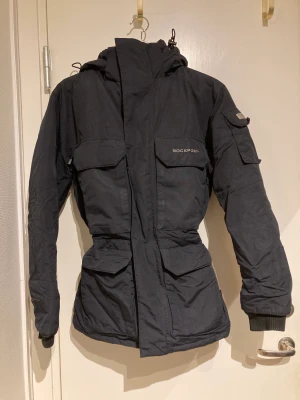 Bortskänkes! - Rockport jacka i unisex modell Storlek XXS (stor i storleken) Dragkedjan är lite seg och saknar den man drar i (se bild). Annars hel och ren! Bortskänkes mot avhämtning eller frakt