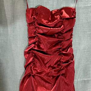Röd festklänning som går att variera bredden på över bröstet då den har knytning bak (se bild). Medföljer gör också en matchande shal. 