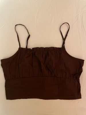 Topp från H&M, storlek 38  - Kort brun topp, bra skick, aldrig använd. 