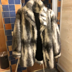 Pälsjacka  - Snygg fuskpälskappa i gråvitt, varm och skön. Går lite över rumpan 