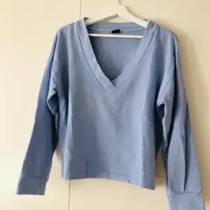 En v-ringad ljusblå tröja i semester material från Ginatricot i storlek S. Tröjan består av 100% bomull och är i fint skick! 
