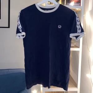 Fred Perry T-shirt mörkblå  - Mörkblå Fred Perry T-shirt som är i ett bra skick, säljer då den inte passar längre!