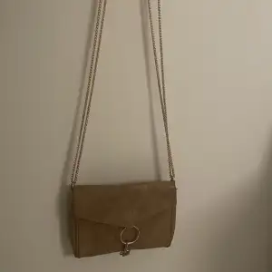 En handväska från gina tricot. Den är i färgen brun/guldinslag som syns bättre på andra bilden som är tagen med blixt. 