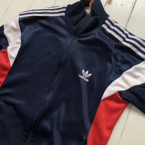 Adidas tracktop - Säljer en jävligt snygg adidas zip-up med ett schysst tryck på ryggen. Har inget märkvärdigt slitage. Köpte den på beyond retro för några år sedan.