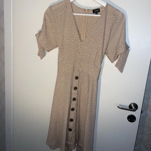 Klänning - Klänning från bubbleroom. Dustypink med bruna prickar. Band i midjan och runt armarna så man själv kan välja hur hårt det ska sitta. Använd ett fåtal gånger.