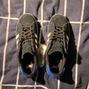 Adidas Campus ADV X MXA storlek 41 1/3 (eur) - Ett par helt nya adidas sneakers gjorda av mocka. De har genomskinlig sula och blå läderhäl. Storlek 41 1/3 (eur)    Lappen är kvar men kartongen är tyvärr ej tillhörande. Jämförspris 999 kr på Junkyard. Öppen för diskution angående priset.