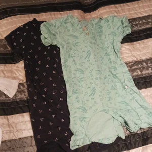 2 st bodies barn - Från vänster: 1 st mörkblå/svart med ankarmotiv storlek 80. 1 st grön med naturmotiv storlek 70 (stor storlek) sparsamt använda.