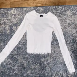 En vit lång ärmad tröja med en öppen rygg.