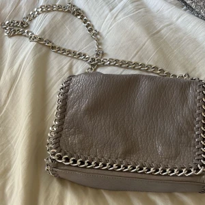 Tiamo väska - LÅNADE BILDER  Intressekoll på min Tiamo väska jag aldrig använder. Inte min stil typ så ja använder den inte men ja tycker den är jätte fin o är osäker om ja vill sälja. Men jag behöver pengar Inga tecken på att den är använd. Grå beige färg