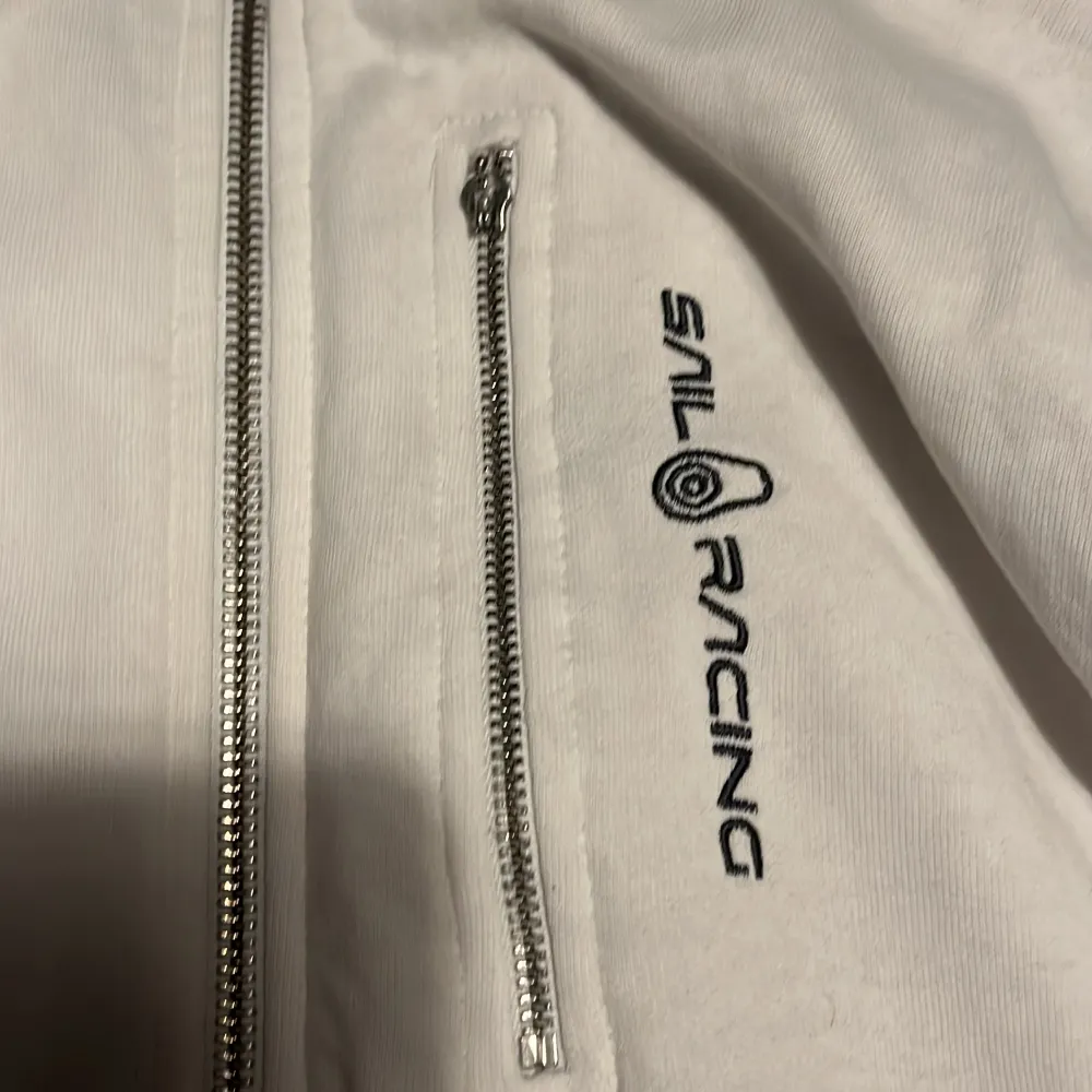 En vit sail racing hoodie som jag Hartvig över ett år. Den är i ganska bra skick men dragkedjan på den lilla fickan är av men har kvar den och den är jätte enkel att sätta på. Skick 7/10. Hoodies.